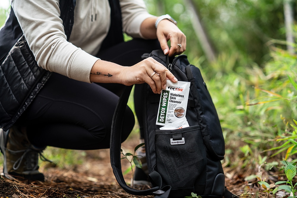 A female hiker is pulling out detox wipes from her backpack.
