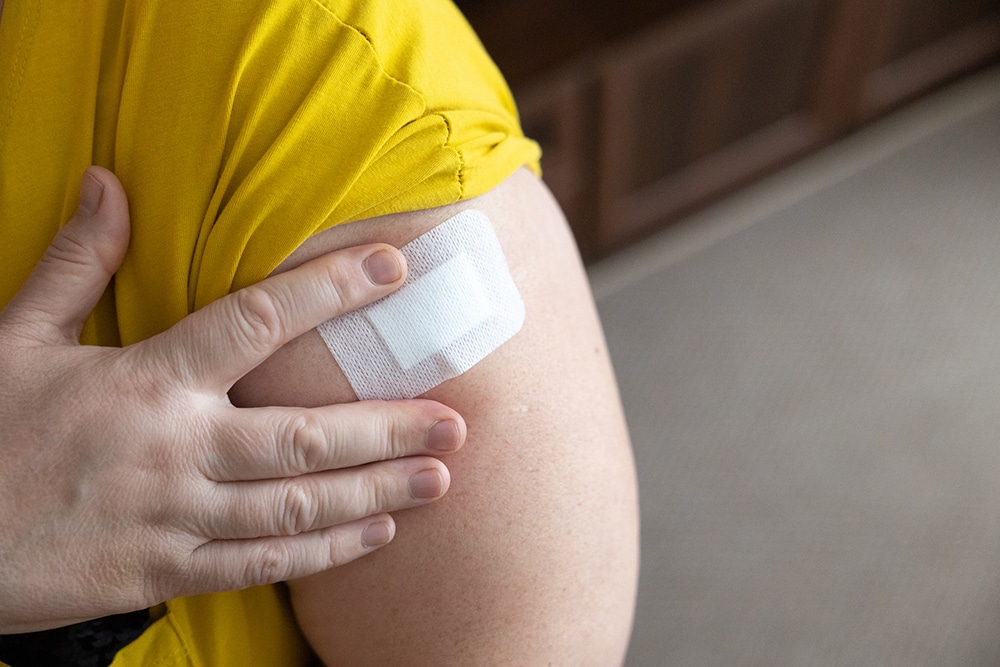 A closeup look of an adhesive wound bandage on a lady's arm.