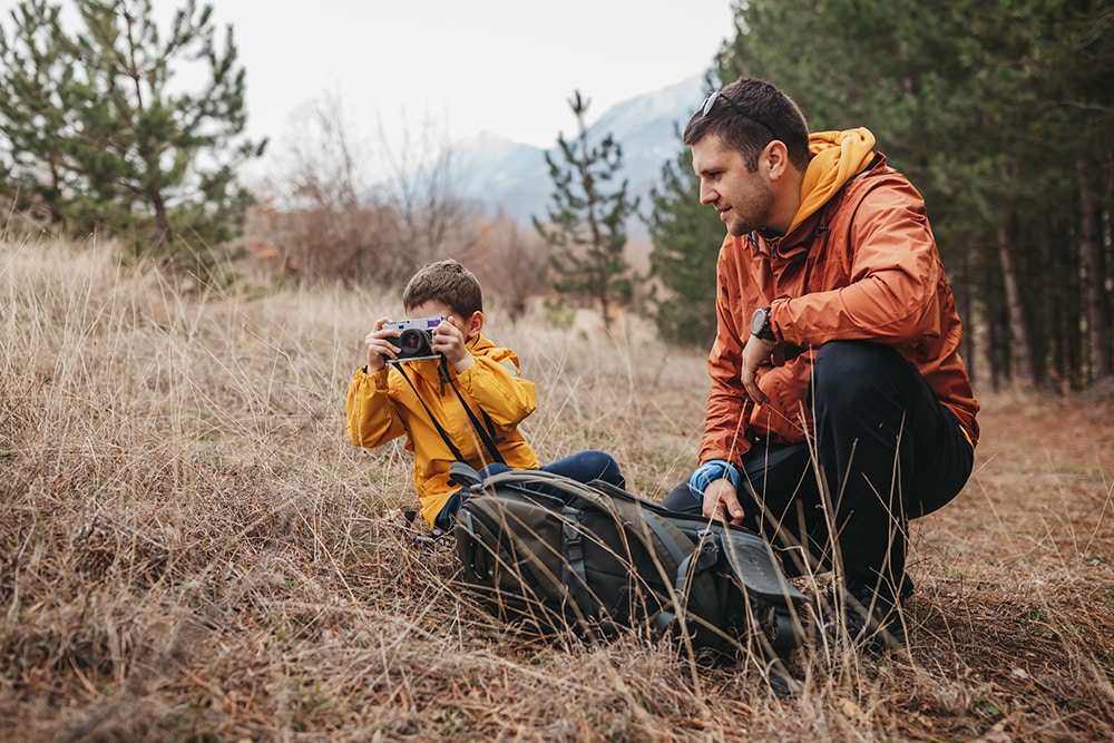 Young father and little son with camera in nature.