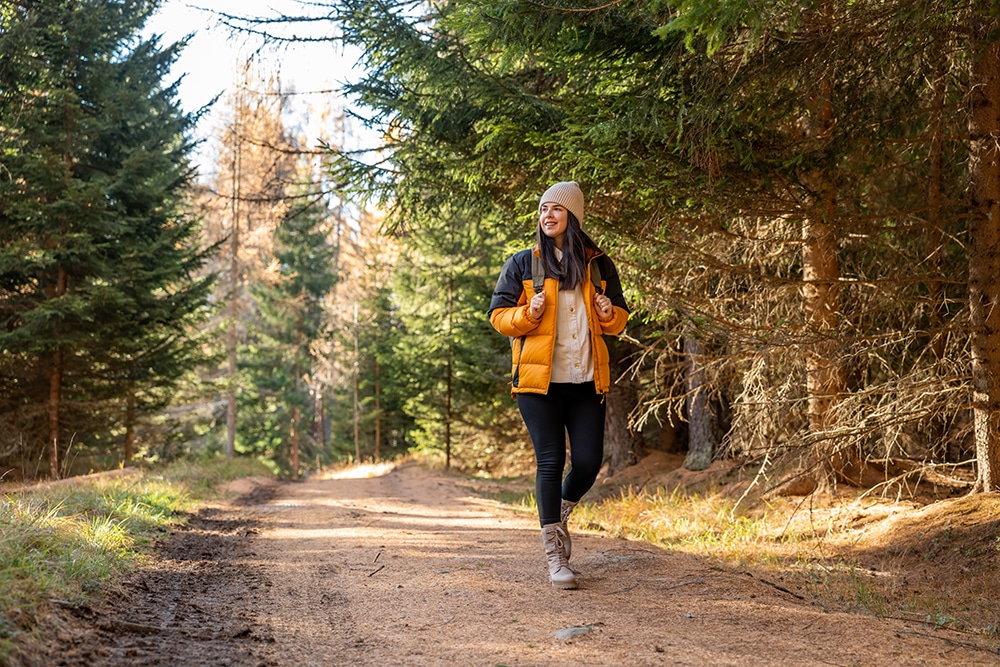 A woman with a backpack is trekking along a woodland path during spring.